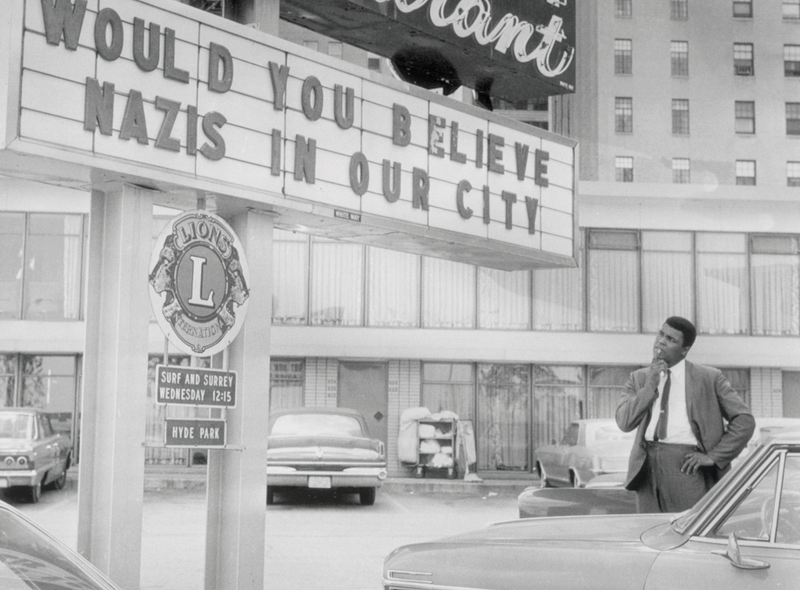 Heavyweight champion Cassius Clay (Muhammad Ali) casts a wondered look at a marquee that reads "WOULD YOU BELIEVE NAZIS IN OUR CITY" at the entrance to a South Side motel. Clay is in Chicago attending a Black Muslim convention at the International Amphitheater. The Champ, who takes off for Germany on August 29, drew a standing ovation when he addressed a huge crowd at the convention.Getty Images